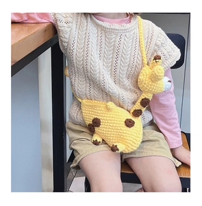 Detail view of a yellow knitted giraffe crossbody bag with crochet patterns for kids