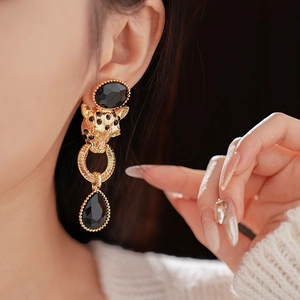 Detail shot of vintage gold leopard head earrings with black gemstone drops on model