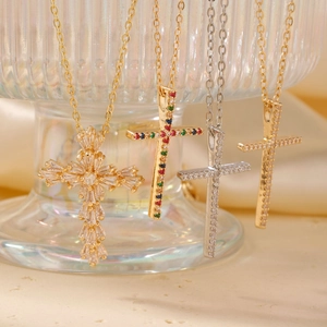 Elegant gold and silver cross necklaces with colorful zircon stones on textured glass