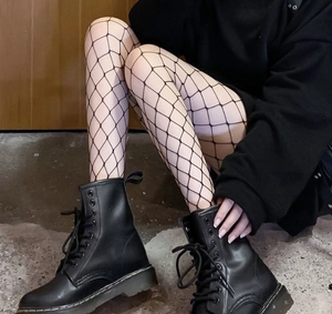 Detail of black large mesh fishnet stockings with rhinestones and black combat boots