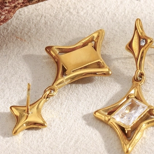 Macro shot of gold-plated star pendant earrings with clear square zircon setting