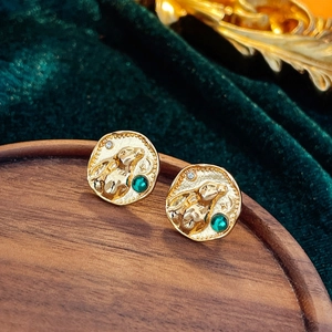Gros plan de boucles d'oreilles lapin dorées avec pierres vertes sur velours vert
