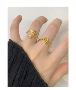 Detail of adjustable gold branch and leaf open ring set worn on a female hand