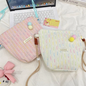 Detail of tweed crossbody phone bags in pink and white with adjustable cord straps