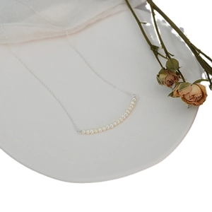 Minimalist freshwater pearl necklace with silver chain on white ceramic plate