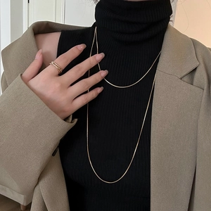 Elegant gold snake bone chain necklace and multi-layer ring set worn with a blazer