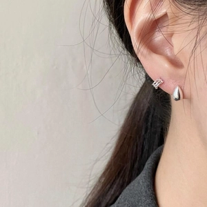 Close-up of model wearing minimalist silver water drop stud and rectangular hoop earrings