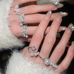 Macro shot of layered silver rings featuring white pearls and star zircon on hand