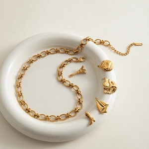 18K gold plated stainless steel necklace with Eiffel Tower and globe charms in a dish