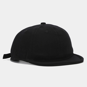 Dettaglio del cappello in tela nera lavata con visiera corta e cinturino regolabile