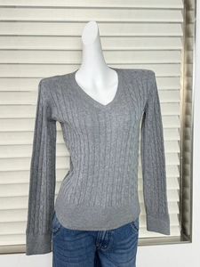 Detailed close-up of grey cable knit texture and V-neck design on slim fit women sweater