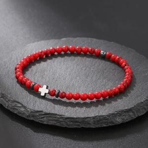 Macro view of red turquoise stone beads and silver cross pendant on a dark rock plate
