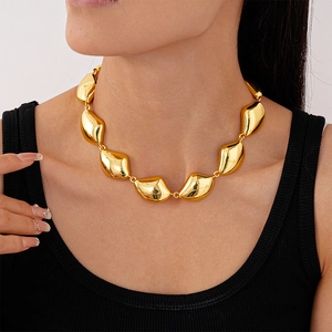Primo piano della collana a maglie geometriche irregolari dorate sul collo del modello