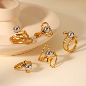 Detail of two-tone stainless steel rings with gold twisted bands and silver sphere beads