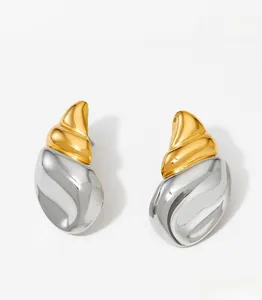 Detailed macro view of two-tone gold and silver conch shell stud earrings in stainless steel