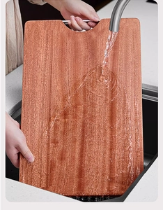 Water rinsing a solid ebony wood cutting board in kitchen sink showing wood grain texture