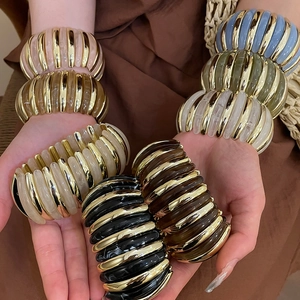 Close-up of stacked colorful acrylic resin ribbed stretch bracelets with gold metal accents
