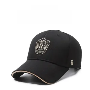Detail of shield embroidery on black baseball cap with beige brim piping and side logo