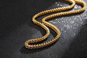 Detailed close-up of a premium gold braided snake chain necklace on a black background