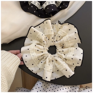 Close-up of polka dot fabric scrunchies with delicate white lace trim and layered texture