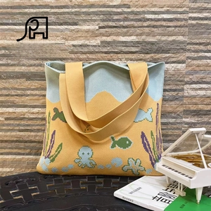 Detail of knitted tote bag featuring ocean octopus and fish patterns with yellow handle
