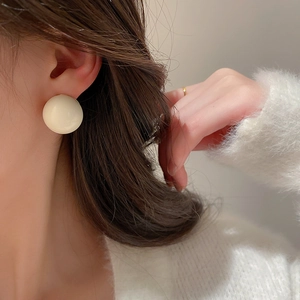 Gros plan de boucles d'oreilles carrées blanc crème portées par un mannequin en gros plan