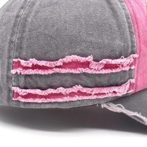 Detail of distressed grey denim baseball cap with pink fabric patchwork and frayed edges