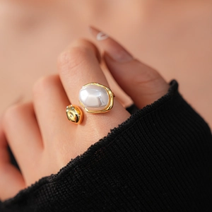 Gros plan sur une bague ajustable dorée avec perle ovale portée par un mannequin