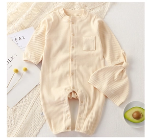 Detail of ribbed cotton baby romper and matching knotted hat set in soft cream white