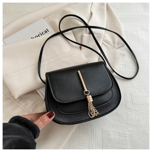 Detail of black matte leather saddle bag with gold metal fringe and elegant strap