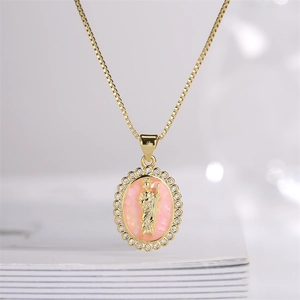 Close-up of gold-plated pendant with pink inlay, saint relief, and small crystals