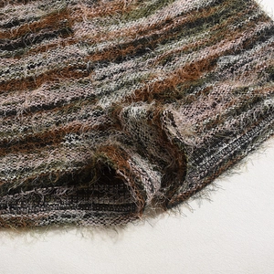Macro detail of textured fringe knit fabric in brown, olive, and pink striped patterns