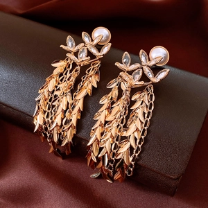 Macro detail of 18K gold-plated floral earrings with pearl and crystal tassel chain