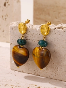 Detailed close-up of tiger eye heart earrings on a natural stone display background