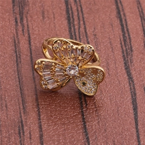 Macro detail of gold flower ring with baguette and round zircons on a leather surface
