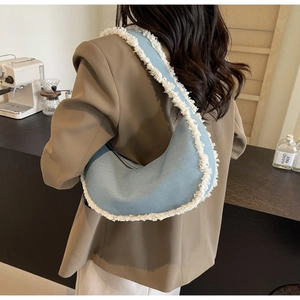 Détail du sac hobo croissant en denim bleu clair avec bords effilochés blancs tendance