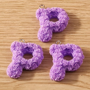 Detailed view of three purple letter P pendants with 3D rose textures for DIY jewelry