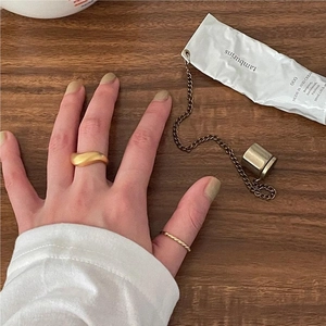 Detail of minimalist gold twisted rope ring and wavy matte band on wooden surface