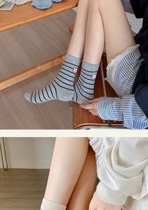 Detail of grey striped cotton socks and beige ribbed knit socks in a cozy home setting