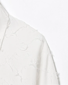 Gros plan détaillé sur la texture du tissu blanc à franges et la broderie raffinée