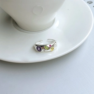 Detail of S925 sterling silver ring with colorful stones on a white coffee cup