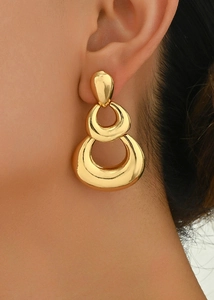Close-up of triple-layered golden teardrop dangle earrings on a female model's ear