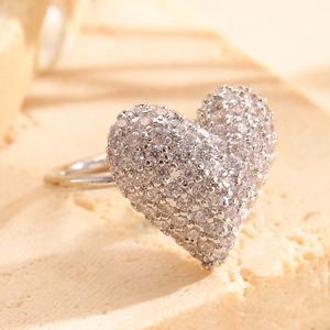 Macro shot of silver heart clip earrings with pavé-set zircons on a stone background