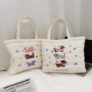 Détail de sacs fourre-tout matelassés avec broderies chat et chien sur fond blanc