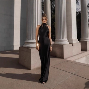 Detail of elegant black satin halter neck dress with slim fit floor-length design
