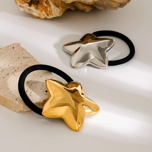 Close-up of gold and silver star-shaped charms on minimalist hair ties over beige stone