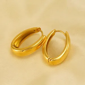 Polished gold stainless steel oval hoop earrings on elegant textured champagne fabric