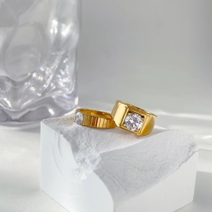 Detail of luxury gold couple rings with gear texture and one-carat diamond on white stone