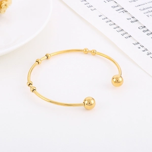 Detailed view of an 18K gold-plated C-shaped stainless steel bracelet with bead accents