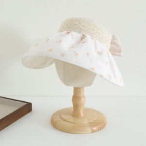 Detail of girl's sun hat with orange floral print and delicate lace bow decoration
